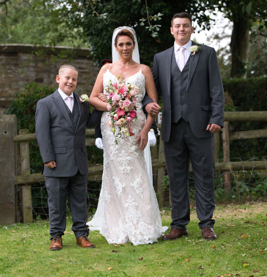 The bride poses with her two sons before walking down the aisle at lime breeze wedding venue Macclesfield