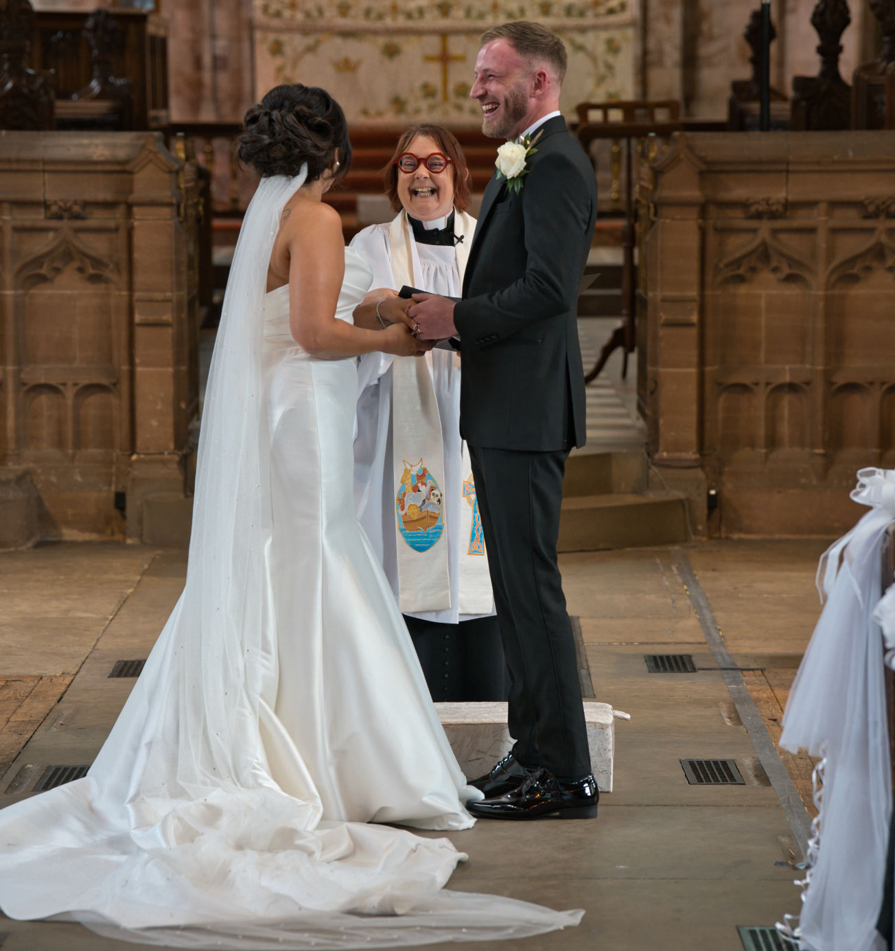 The bride and groom with the Vicar enjoy a funny moment at the wedding at St George's Church, London Road, Stockport