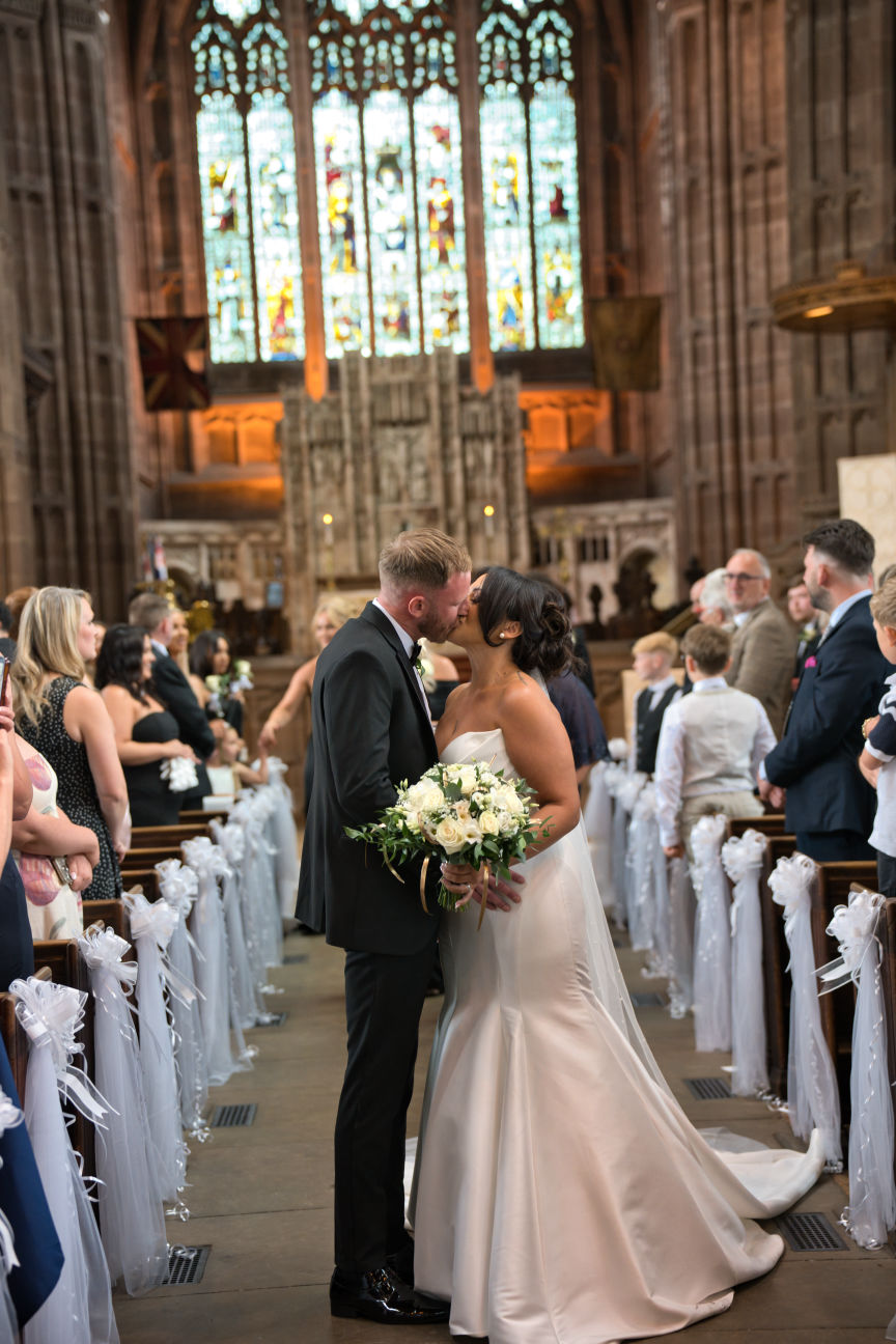 A bride and groom kiss in the aisle at St George's Church London Road, Stockport