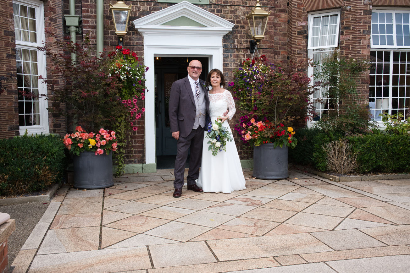 A bride and groom stand out there the entrance of the Stanneylands Hotel Wilmslow